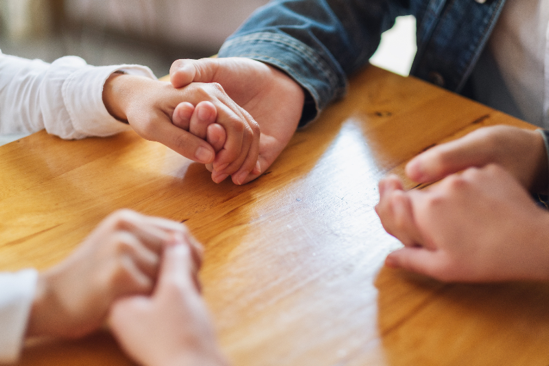 Group of people sitting in a circle holding hands in therapy session