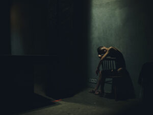 woman sitting alone in dark room with crocodile addiction
