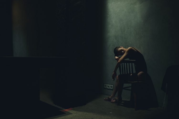 woman sitting alone in dark room with crocodile addiction